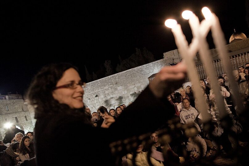 A Jewish woman lights a candle for the festival of Hanukkah at the Western Wall Plaza in Jerusalem. (Marco Longari/AFP via Getty Images)