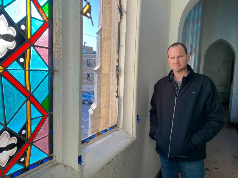 The Rev. Wes Fowler, senior pastor of First Baptist Church, poses for a photo next to a broken stained glass window, in the sanctuary of the church, in the aftermath of tornadoes that tore through the region, in Mayfield, Ky., Monday, Dec. 13, 2021. (AP Photo/Holly Meyer)