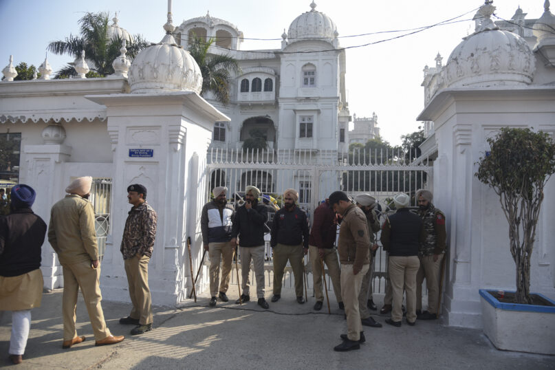 Indian policemen stand guard outside the office of Shiromani Gurdwara Parbandhak Committee, the organization responsible for the management of Sikh temples near the Golden Temple in Amritsar, India, Sunday, Dec.19, 2021. A man was beaten to death Saturday after he allegedly attempted to commit a sacrilegious act inside the historic temple, one of Sikhs' most revered shrines. (AP Photo/Prabhjot Gill)