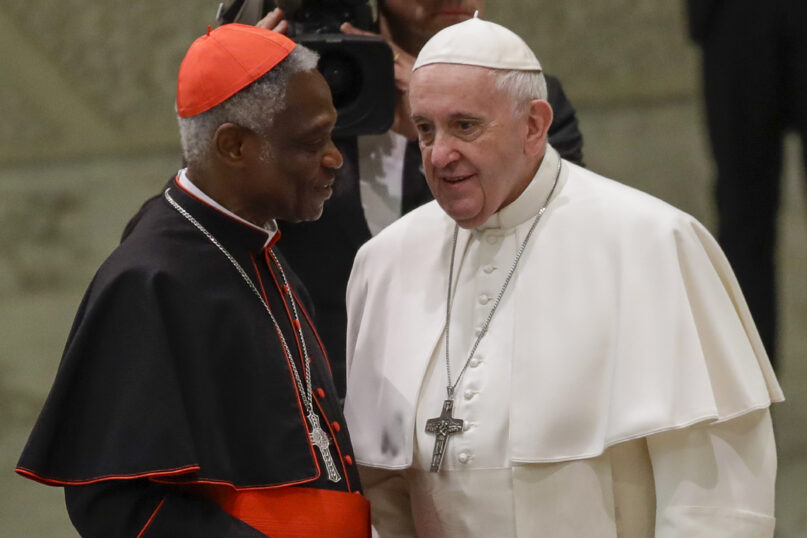 FILE  - Pope Francis talks with Cardinal Peter Kodwo Appiah Turkson during his weekly general audience, in Paul VI Hall at the Vatican, Wednesday, Jan. 15, 2020. Pope Francis on Thursday, Dec. 23, 2021 removed the head of the Vatican office that handles the high-priority issues of migration, environment and COVID-19 and put a trusted cardinal and one of the Holy See’s most influential nuns at the helm instead, albeit temporarily.rnThe Vatican said Francis thanked Cardinal Peter Turkson for his service, but had decided on new leadership after an initial five-year term and following the results of an internal investigation.  (AP Photo/Alessandra Tarantino, File)