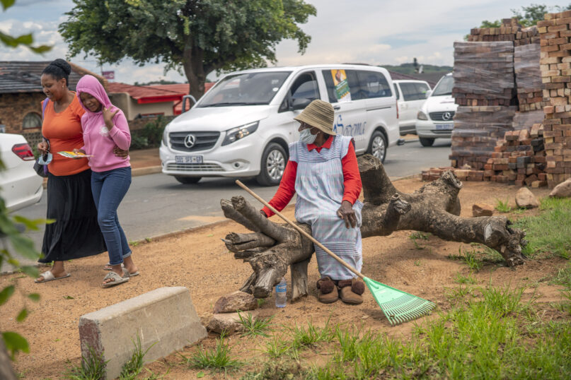 FILE - A woman watches hearses drive in convoy through Soweto, South Africa, Tuesday Dec. 7, 2021. Over 40 hearses took part in what was a COVID-19 vaccine awareness campaign, with the slogan: 