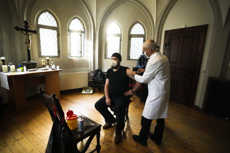 A doctor gives a man a vaccination against coronavirus inside the St. Petri church in Chemnitz, Germany, Sunday, Dec. 12, 2021. Pastor Christoph Herbst at St. Petri church is one of several Lutheran leaders who have been promoting vaccinations in a region that is among the hardest hit by the virus. (AP Photo/Markus Schreiber)