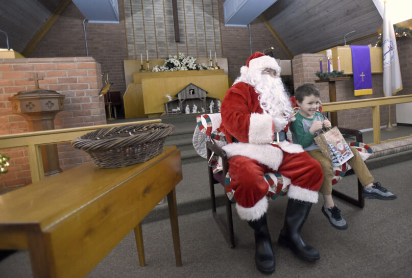 Walker Baker, 5, of Hagerstown, Maryland, visits with Santa Claus, portrayed by volunteer Wayne Hutzell of Williamsport, Maryland, during Prison Fellowship’s Angel Tree event for children of the incarcerated, Dec. 19, 2021, at Hub City Vineyard church in Hagerstown. The Prison Fellowship’s Angel Tree is expected to deliver gifts to about 300,000 kids nationwide this year. (AP Photo/Steve Ruark)
