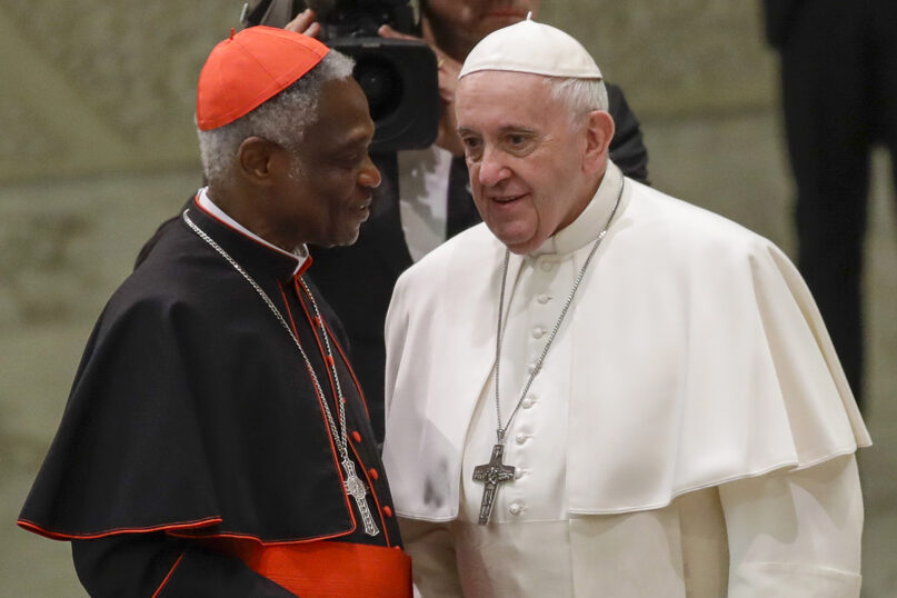 Pope Francis talks with Cardinal Peter Turkson during his weekly general audience, in Paul VI Hall at the Vatican, Jan. 15, 2020. (AP Photo/Alessandra Tarantino)