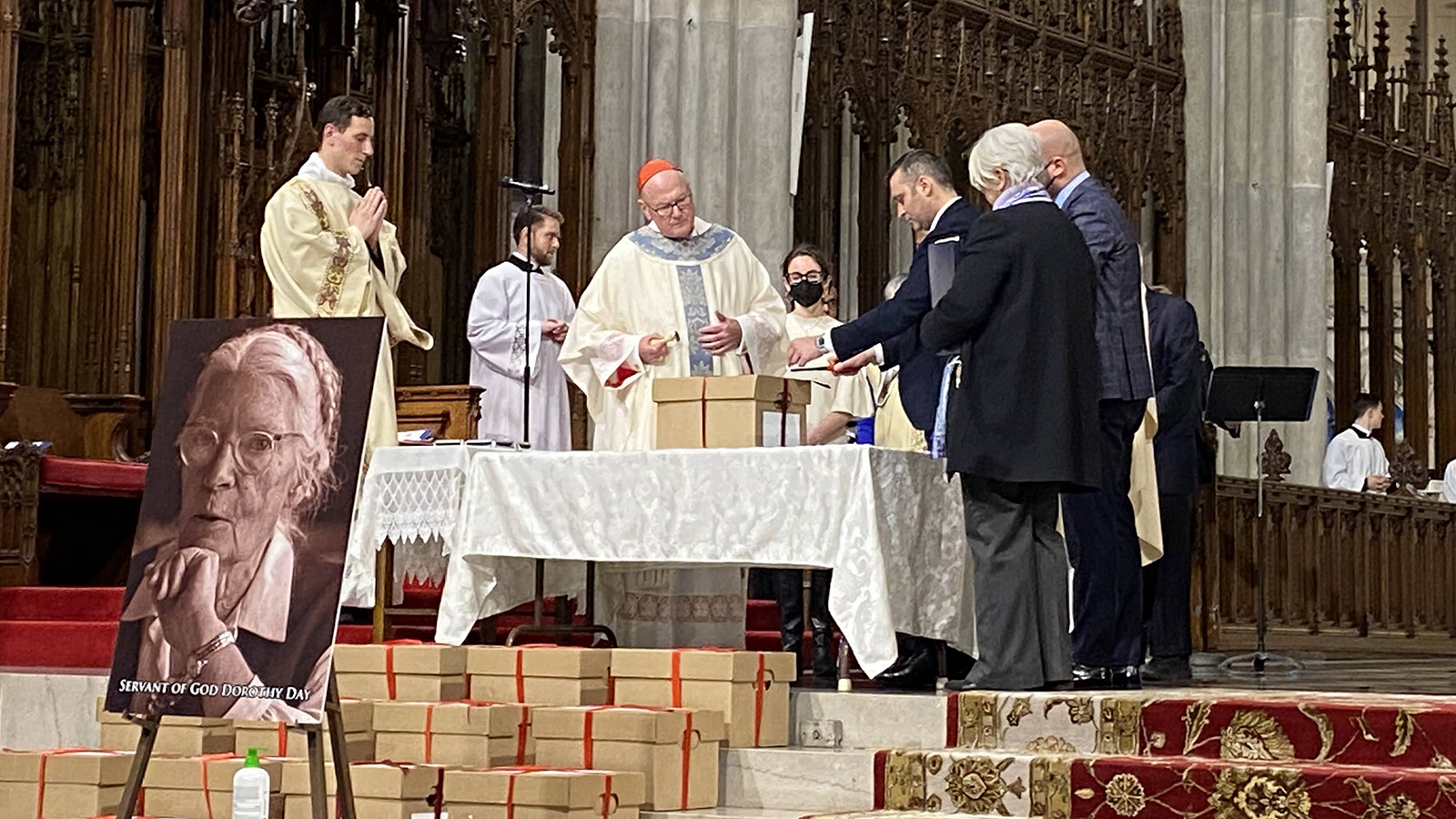 Cardinal Timothy Dolan, center, seals a cardboard box filled with evidence of Dorothy Day’s “reputation for holiness” during a Mass at St. Patrick's Cathedral in New York, Wednesday, Dec. 8, 2021. The boxes will be sent to the Congregation for the Causes of Saints in Rome. RNS photo by Renée Roden