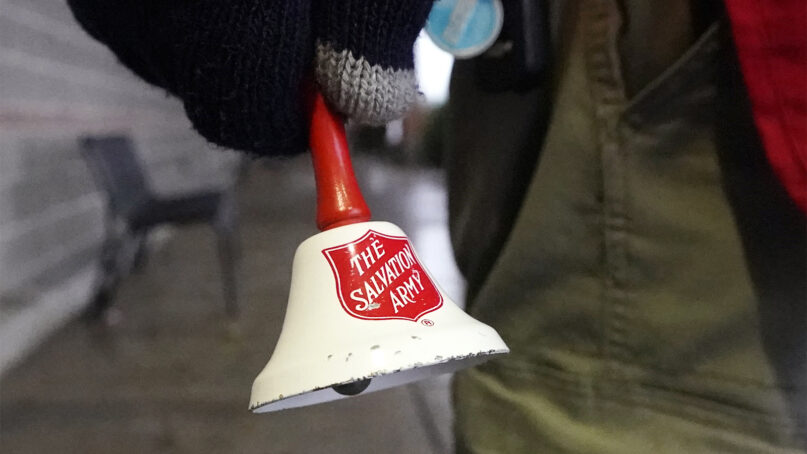 A Salvation Army bell is rung by Michael Cronin as he staffs the charity's red donation kettle in front of a grocery store, Dec. 8, 2020, in Lynden, Washington. (AP Photo/Elaine Thompson, File)