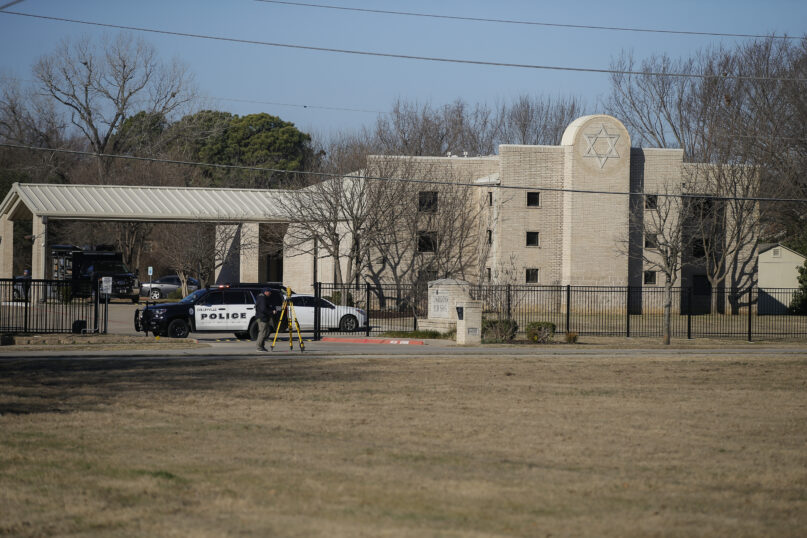 Law enforcement officers process the scene in front of the Congregation Beth Israel Synagogue,  Jan. 16, 2022, in Colleyville, Texas. A man held hostages for more than 10 hours Saturday inside the temple. The hostages were able to escape, and the hostage-taker was killed. (AP Photo/Brandon Wade)