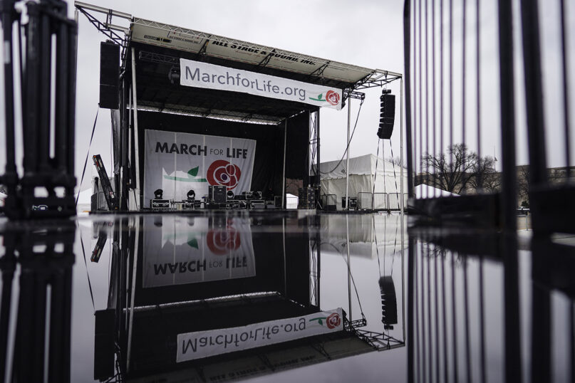 A stage in place for the March for Life rally is reflected on a wet camera stand on the National Mall in Washington, Thursday, Jan. 20, 2022. The March for Life takes place Friday, Jan. 21, 2022. (AP Photo/Carolyn Kaster)