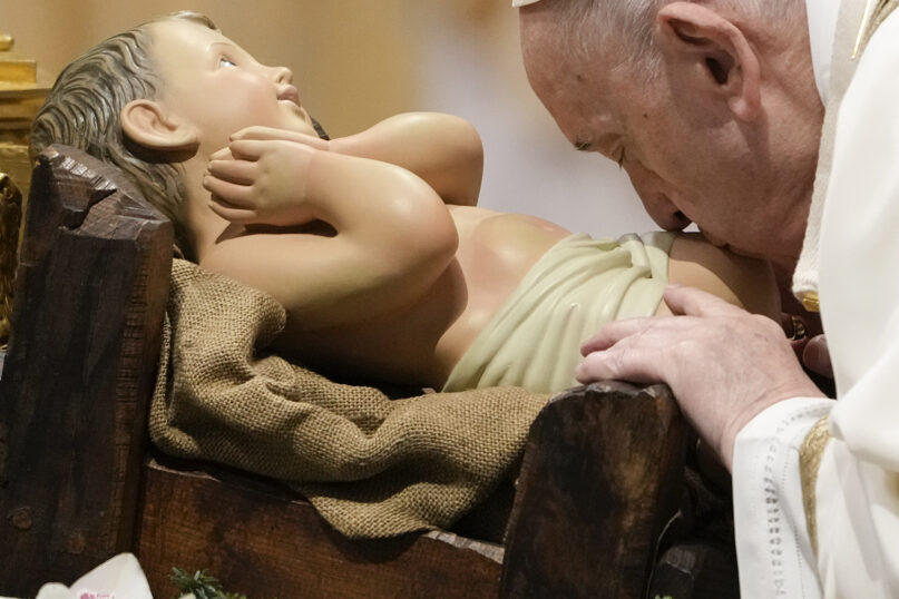 Pope Francis kisses a statue of baby Jesus as he celebrates an Epiphany Mass in St. Peter's Basilica, at the Vatican, Jan. 6, 2022. (AP Photo/Gregorio Borgia)
