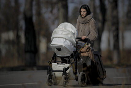 A woman pushes a baby stroller after crossing the border from Ukraine at the Romanian-Ukrainian border, in Siret, Romania, Friday, Feb. 25, 2022. Thousands of Ukrainians are fleeing from war by crossing their borders to the west in search of safety. They left their country as Russia pounded their capital and other cities with airstrikes for a second day on Friday. Cars were backed up for several kilometers (miles) at some border crossings as authorities in Poland, Slovakia, Hungary, Romania and Moldova mobilized to receive them, offering them shelter, food and legal help. (AP Photo/Andreea Alexandru)