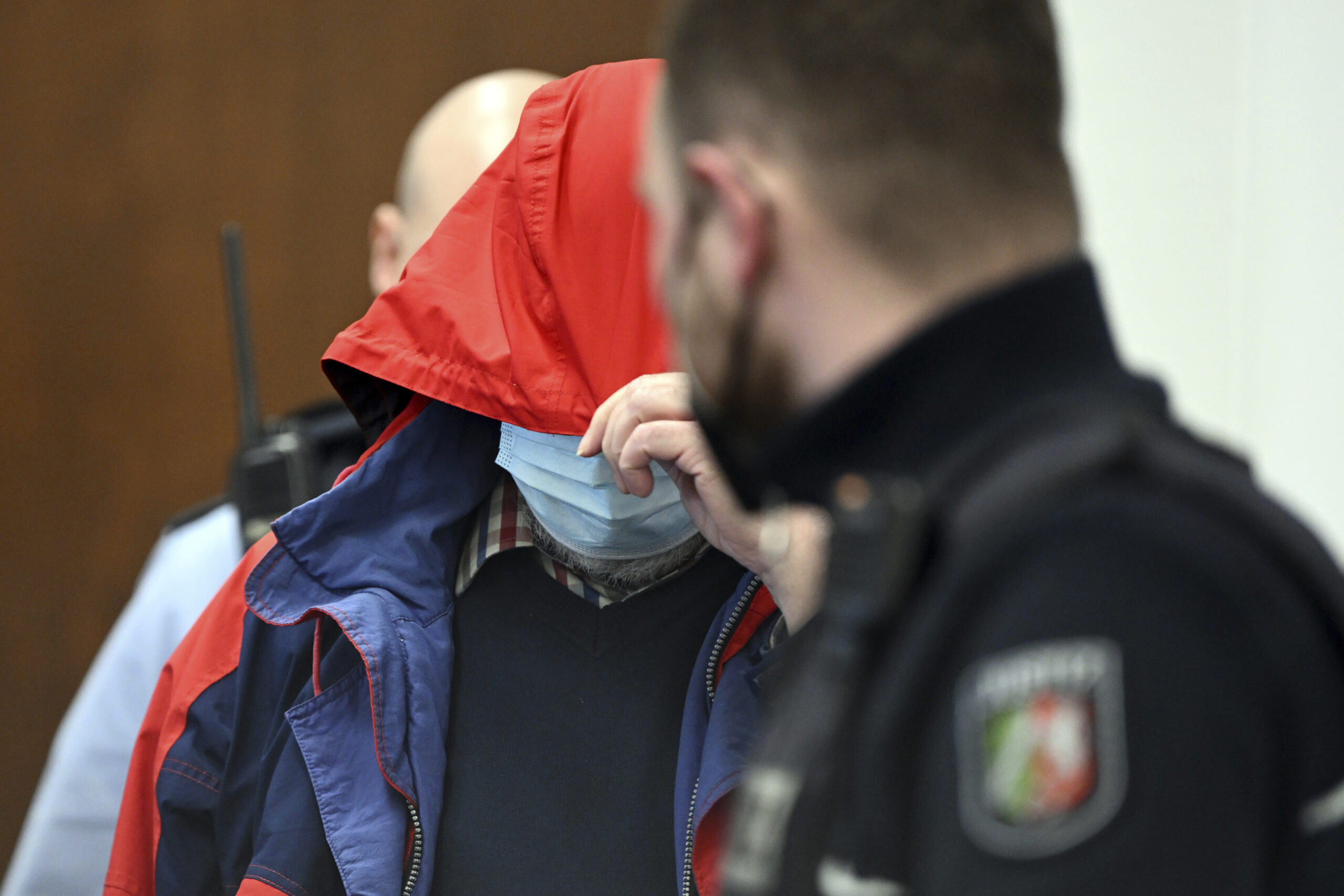 The accused Catholic priest is led into the courtroom in Cologne, Germany, Friday, Feb.25, 2022. On Friday, the Cologne Regional Court sentenced a Catholic priest to twelve years in prison for the sexual abuse of children. The 70-year-old priest must also pay damages of 5,000, 10,000 and 35,000 euros to three female joint plaintiffs. (Federico Gambarini/dpa via AP)