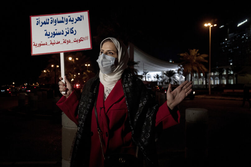 Mashael al-Shuwaihan, who sits on the board of Kuwait's Women's Cultural Society, speaks during an interview, at a protest outside Kuwait's National Assembly, in Kuwait City, Monday, Feb. 7, 2022. Her placard reads: 