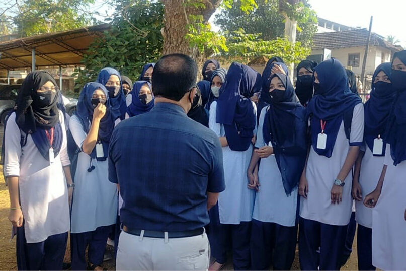 Indian girl students who were barred from entering their classrooms for wearing hijab, a headscarf used by Muslim women, speak to their principal outside the college campus in Udupi, India, Friday, Feb. 4, 2022.  (Bangalore News Photos via AP)