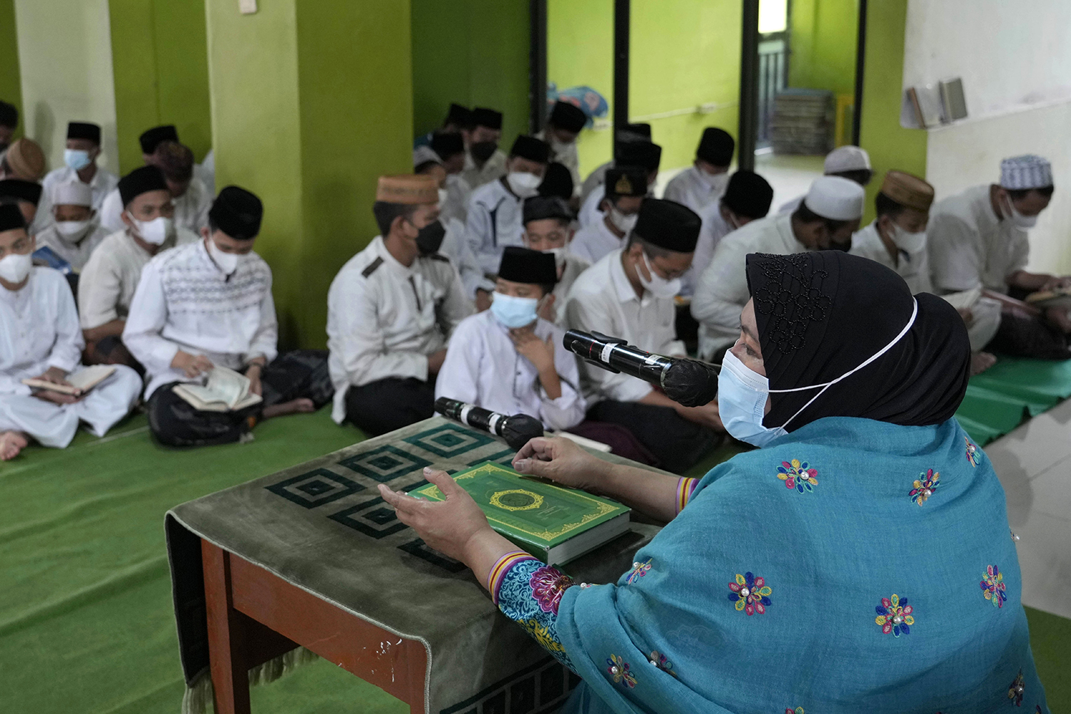 Maria Ulfah, right, sits in front of a class where she teaches Quran recitation at Baitul Qurro Islamic Boarding School in Jakarta, Indonesia, Friday, Feb. 4, 2022. While the most skilled female reciters may attain celebrity-like status in some countries, others are largely confined to private spaces or all-women audiences. (AP Photo/Tatan Syuflana)