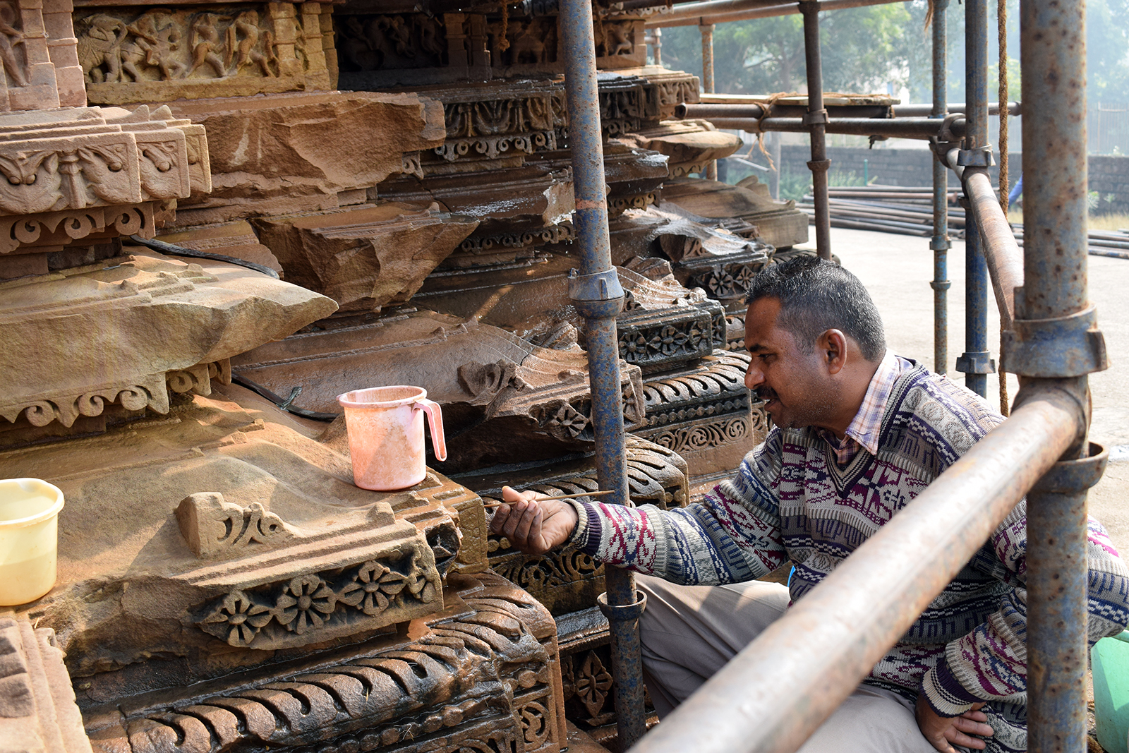 A worker cleans the intricately carved surfaces of a temple in Khajuraho, India, in Dec. 2021. RNS photo by Priyadarshini Sen