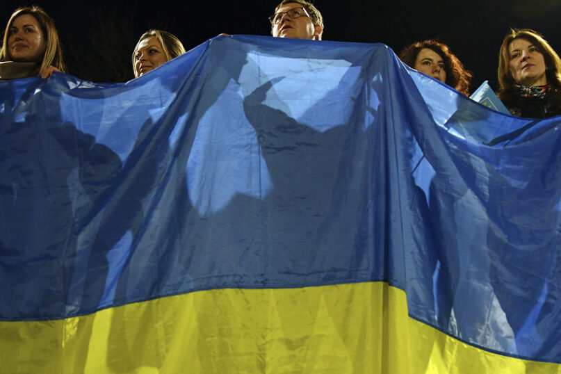 People wave a huge Ukrainian national flag during a rally in Kramatorsk, Ukraine, Feb. 23, 2022. (AP Photo/Andriy Andriyenko)