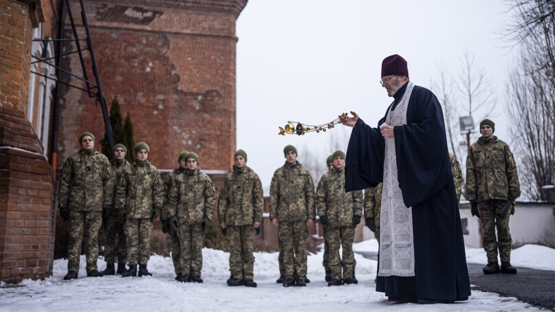 An Orthodox priest blesses Ukrainian Military Air Force University cadets after a monthly memorial service for soldiers who have been killed during fighting against Russia-backed separatists in eastern Ukraine, in Kharkiv, Ukraine, Feb. 3, 2022. Russia maintains it has no intention to attack its neighbor, but demands that NATO not expand to Ukraine and other ex-Soviet nations or deploy weapons there. It also wants the alliance to roll back its deployments to Eastern Europe. (AP Photo/Evgeniy Maloletka)