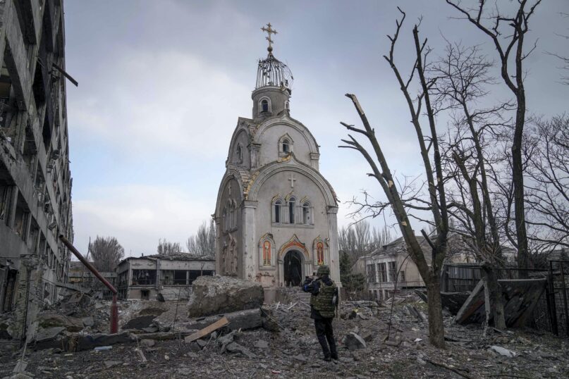 A Ukrainian service member takes a photograph of a damaged church after shelling in a residential district in Mariupol, Ukraine, March 10, 2022.  (AP Photo/Evgeniy Maloletka)