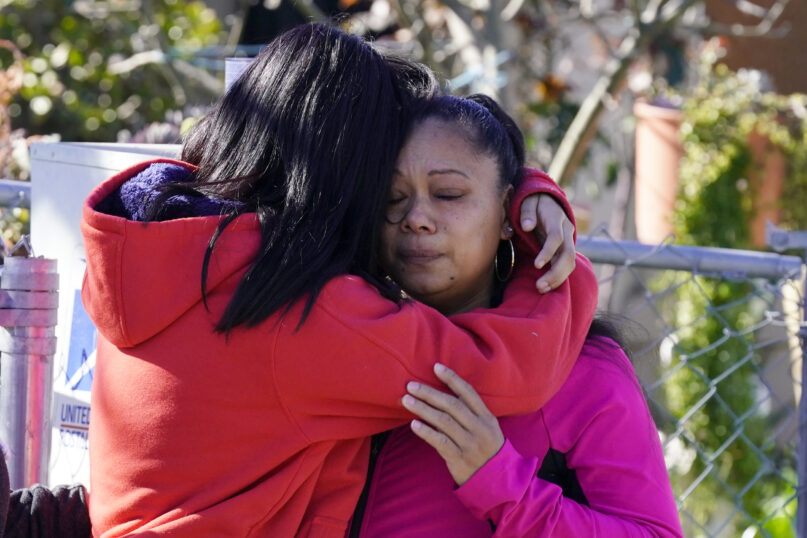 Ana DeJesus, right, is comforted by her daughter, Lizbeth DeJesus after placing a teddy bear and flowers on a memorial at The Church in Sacramento, Calif., on Tuesday, March 1, 2022.   Authorities say a man shot and killed his three daughters, their chaperone and himself during a supervised visit with the girls at the church on Monday. (AP Photo/Rich Pedroncelli)