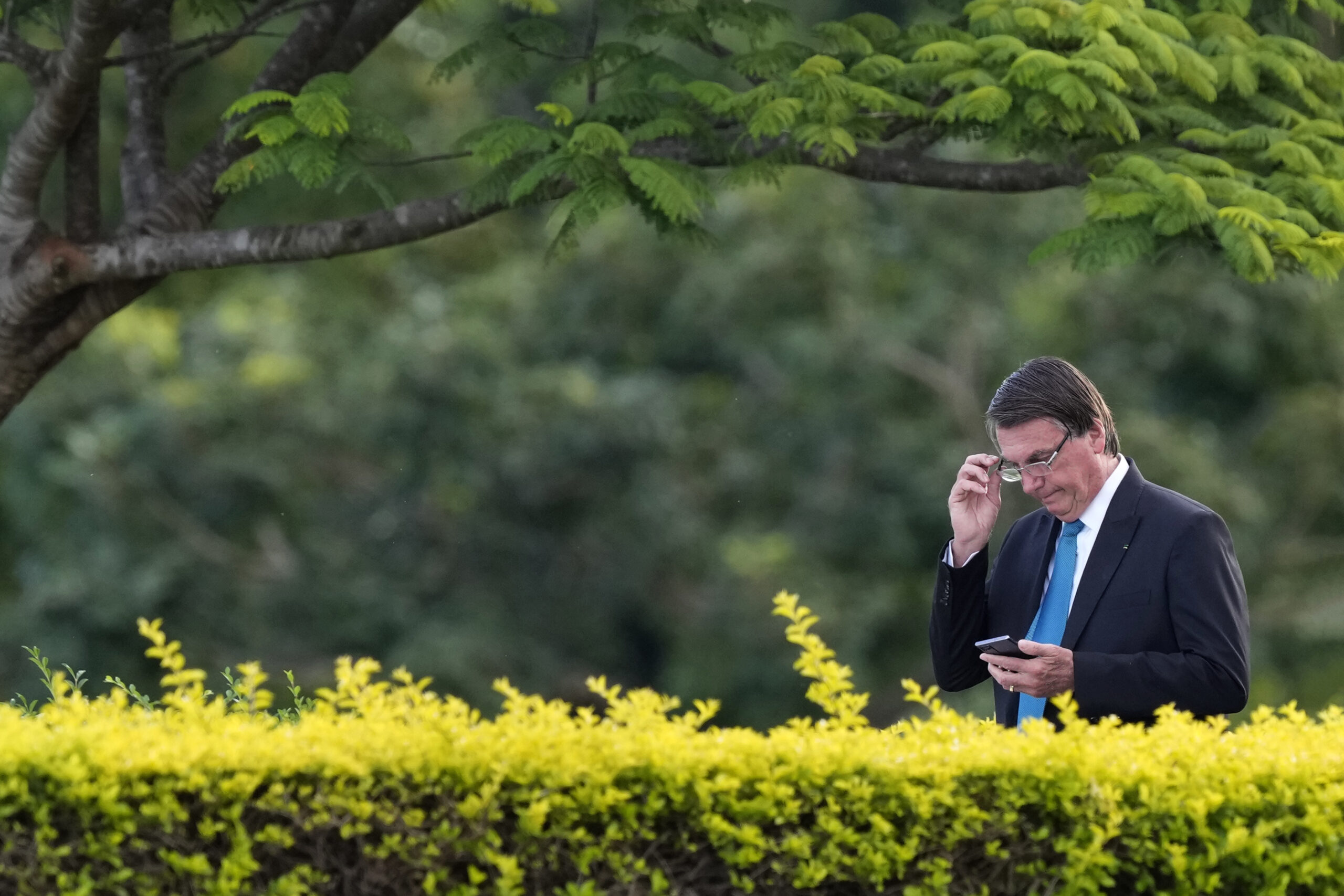 Brazilian President Jair Bolsonaro looks at his cellphone as he arrives for a flag-raising ceremony outside the Alvorada Palace, in Brasilia, Brazil, Thursday, March 17, 2022. (AP Photo/Eraldo Peres)