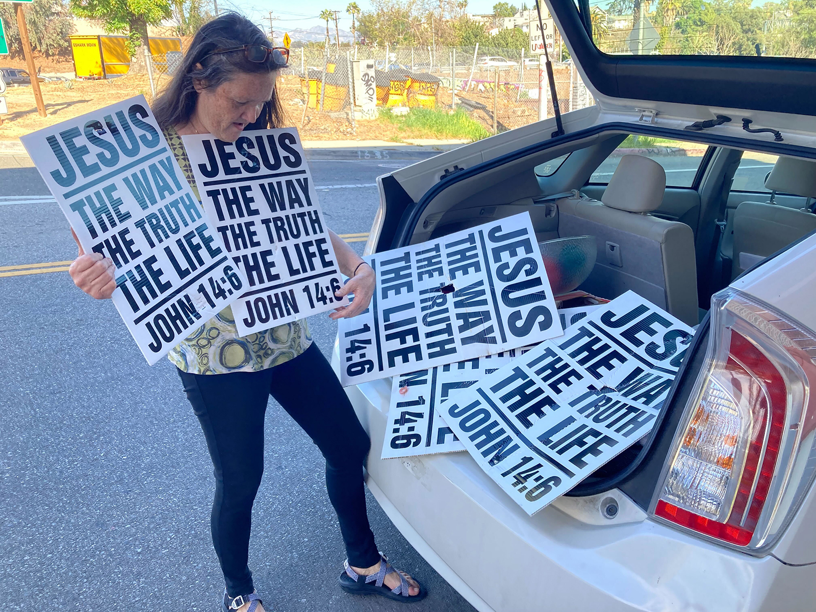 Christine Jones, of Atheists United, puts illegally placed religious material from public streets in Los Angeles in her car after taking them down, Saturday, Feb. 19, 2022. RNS photo by Alejandra Molina