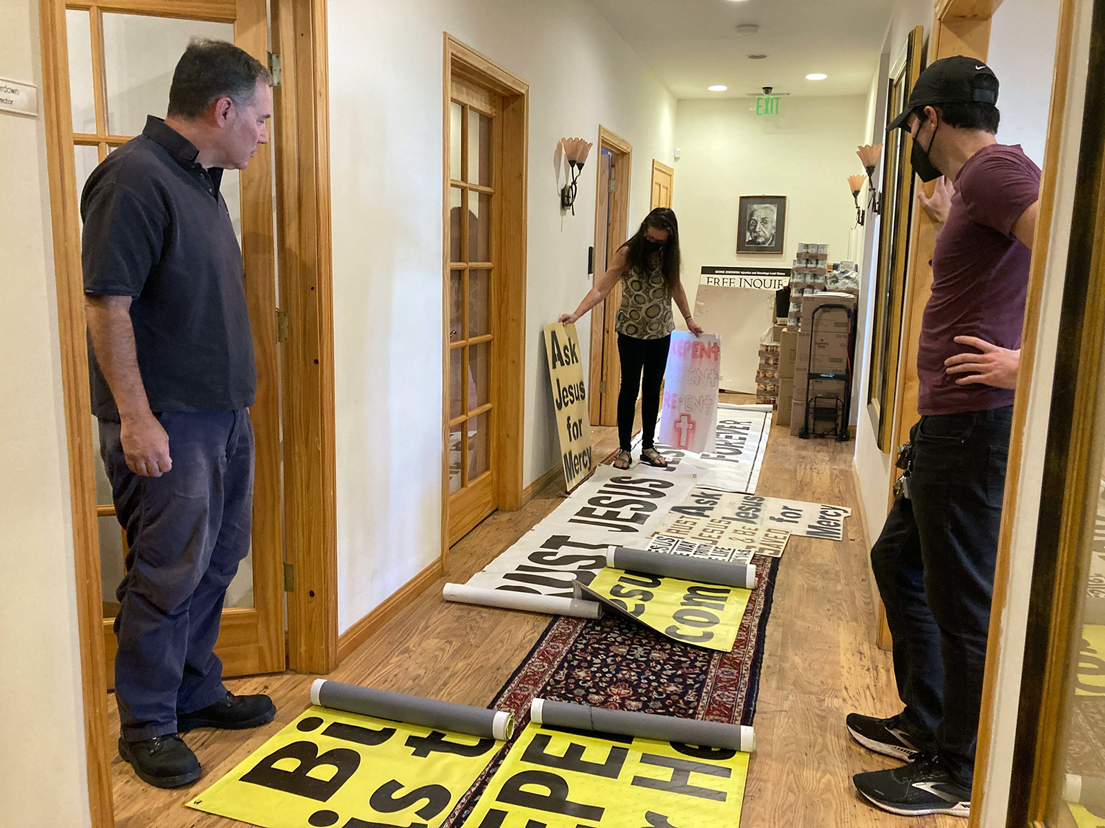Christine Jones, center, of Atheists United, displays illegally placed religious material that the group has removed from public streets in Los Angeles, at the group's offices, Saturday, Feb. 19, 2022. RNS photo by Alejandra Molina