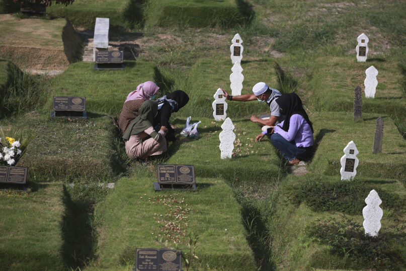 A Muslim family prays at the grave of a relative at a cemetery reserved for those who died of COVID-19, in Medan, North Sumatra, Indonesia, March 31, 2022. Prior to the holy fasting month of Ramadan, Muslims followed local tradition to visit cemeteries to pray for their deceased loved ones. (AP Photo/Binsar Bakkara)