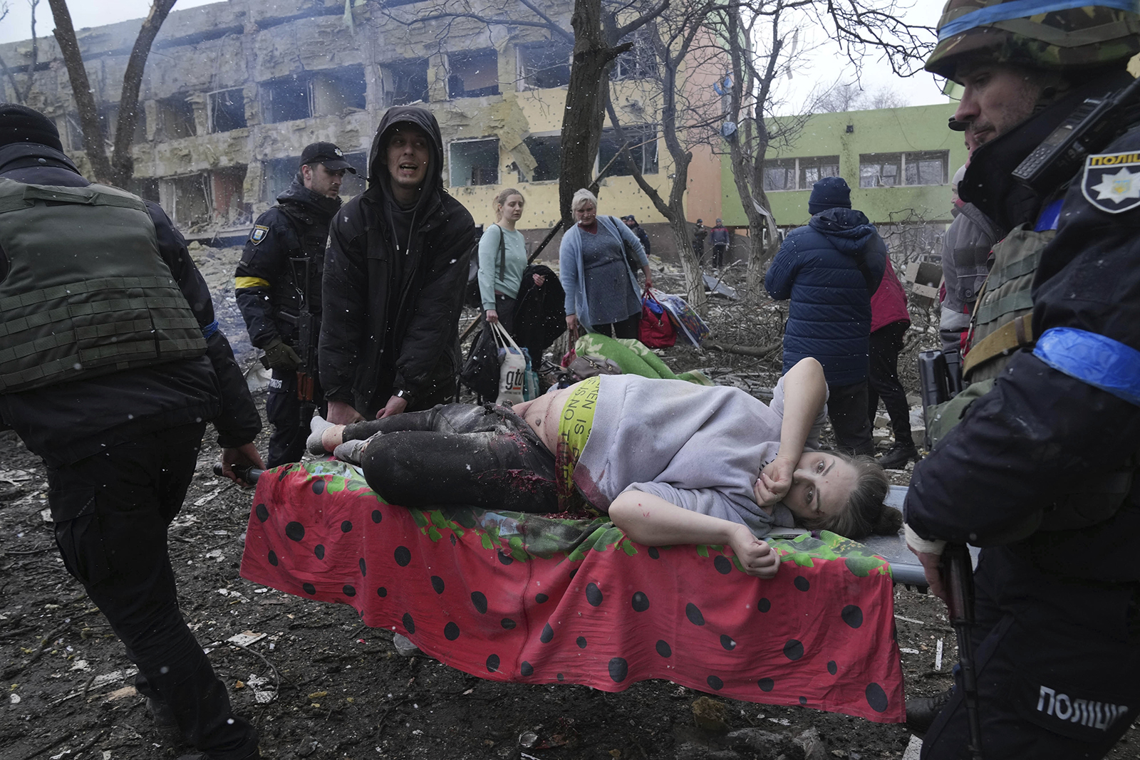 Ukrainian emergency employees and volunteers carry an injured pregnant woman from a maternity hospital in Mariupol, Ukraine, Wednesday, March 9, 2022. A Russian attack severely damaged a maternity hospital in the besieged port city of Mariupol, Ukrainian officials say. (AP Photo/Evgeniy Maloletka)