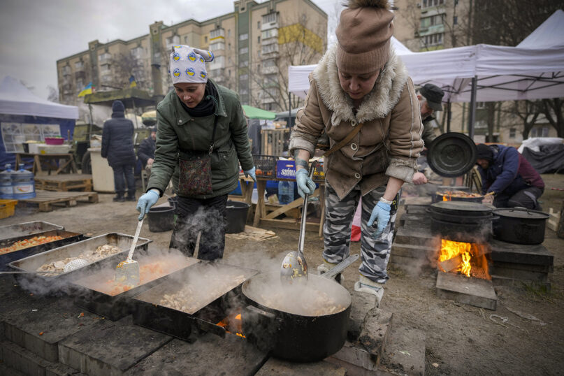 Two women cook outdoors for Ukrainian servicemen and civil defense members serving in Kyiv, Ukraine, March 7, 2022. The United Nations is unable to meet the needs of millions of civilians caught in conflict in Ukraine today and is urging safe passage for people to go “in the direction they choose” and for humanitarian supplies to get to areas of hostilities, according to the U.N. humanitarian chief. (AP Photo/Vadim Ghirda)
