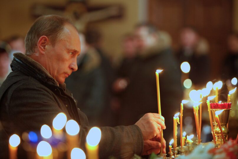Vladimir Putin lights a candle as he attends an Orthodox Church service in 2011. (AP Photo/Alexander Zemlianichenko, pool)