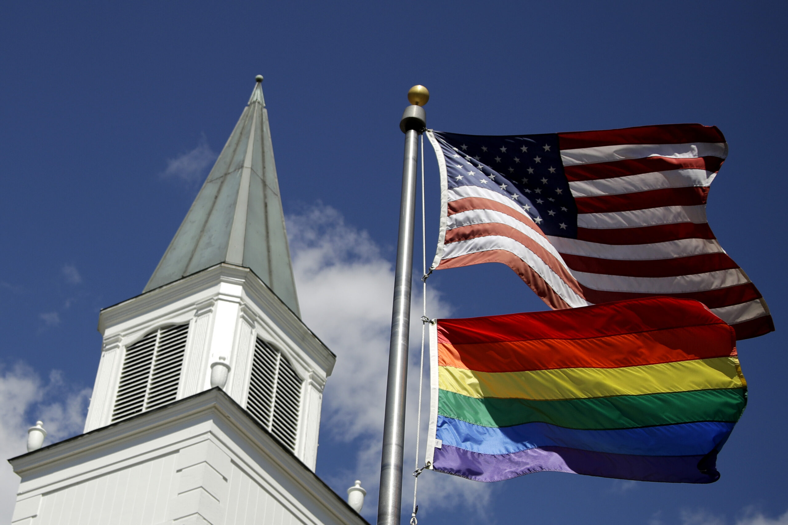 FILE - A gay pride rainbow flag flies along with the U.S. flag in front of the Asbury United Methodist Church in Prairie Village, Kan., on April 19, 2019. The United Methodist Church's Council of Bishops, ending a five-day meeting on Friday, April 29, 2022, acknowledged the inevitable breakup of their denomination, which will gain momentum during the weekend with the launch of a global movement led by theologically conservative Methodists. (AP Photo/Charlie Riedel, File)