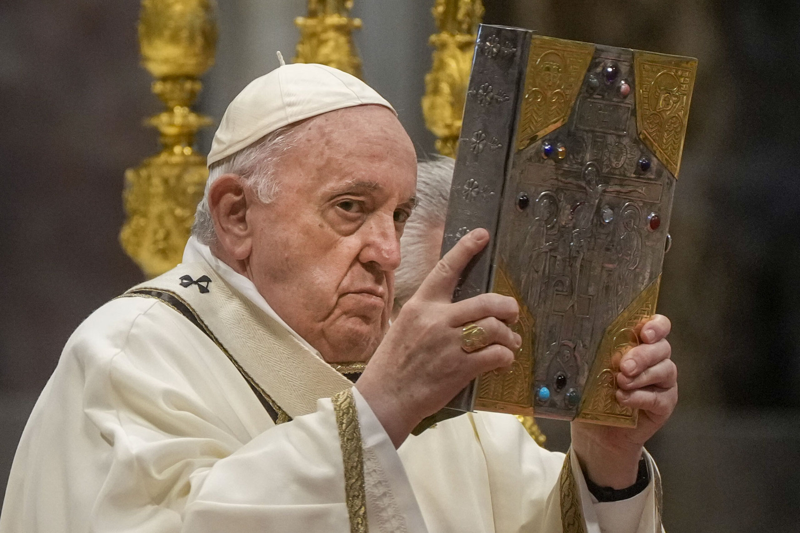 Pope Francis hoists the Gospel book during a Chrism Mass inside St. Peter's Basilica, at the Vatican, Thursday, April 14, 2022. During the mass the Pontiff blesses a token amount of oil that will be used to administer the sacraments for the year. (AP Photo/Gregorio Borgia)