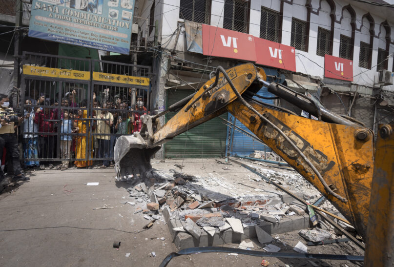 A bulldozer razes structures in the area that saw communal violence during a Hindu religious procession in New Delhi’s northwest Jahangirpuri neighborhood, India, April 20, 2022. Authorities riding bulldozers razed a number of Muslim-owned shops in New Delhi before India’s Supreme Court halted the demolitions, days after communal violence shook the capital and saw dozens arrested. (AP Photo/Altaf Qadri)