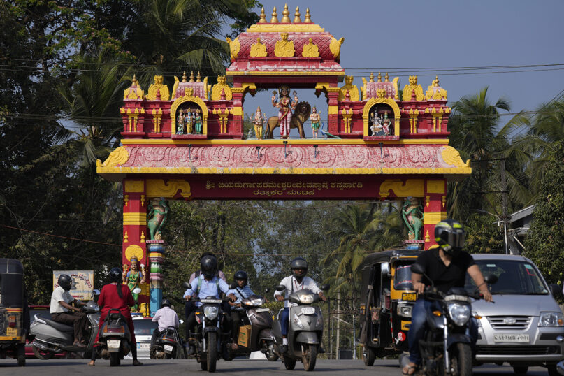 Commuters drive past an arch, decorated with idols of Hindu gods, leading to a Hindu temple in district Udupi, Karnataka state, India, Feb. 25, 2022. An Indian court ruling upholding a ban on Muslim students wearing head coverings in schools has sparked criticism from constitutional scholars and rights advocates amid concerns of judicial overreach regarding religious freedoms. (AP Photo/Aijaz Rahi)