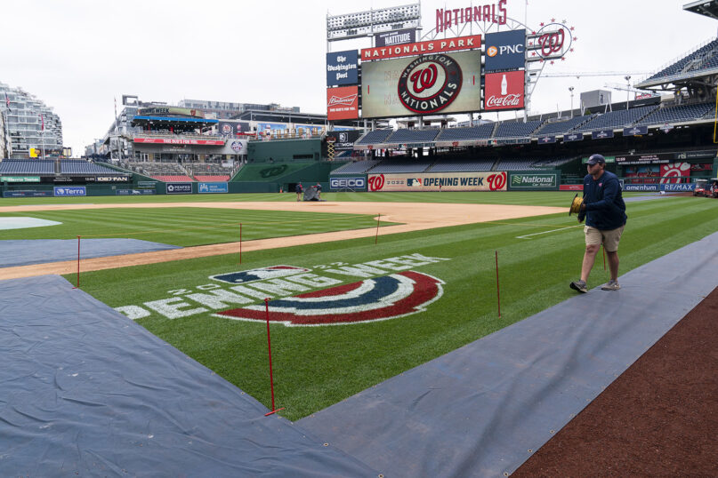 A member of the grounds crew ropes off the on-field logo before baseball workouts at Nationals Park, April 6, 2022, in Washington. The Washington Nationals and the New York Mets are scheduled to play on opening day, Thursday. (AP Photo/Alex Brandon)