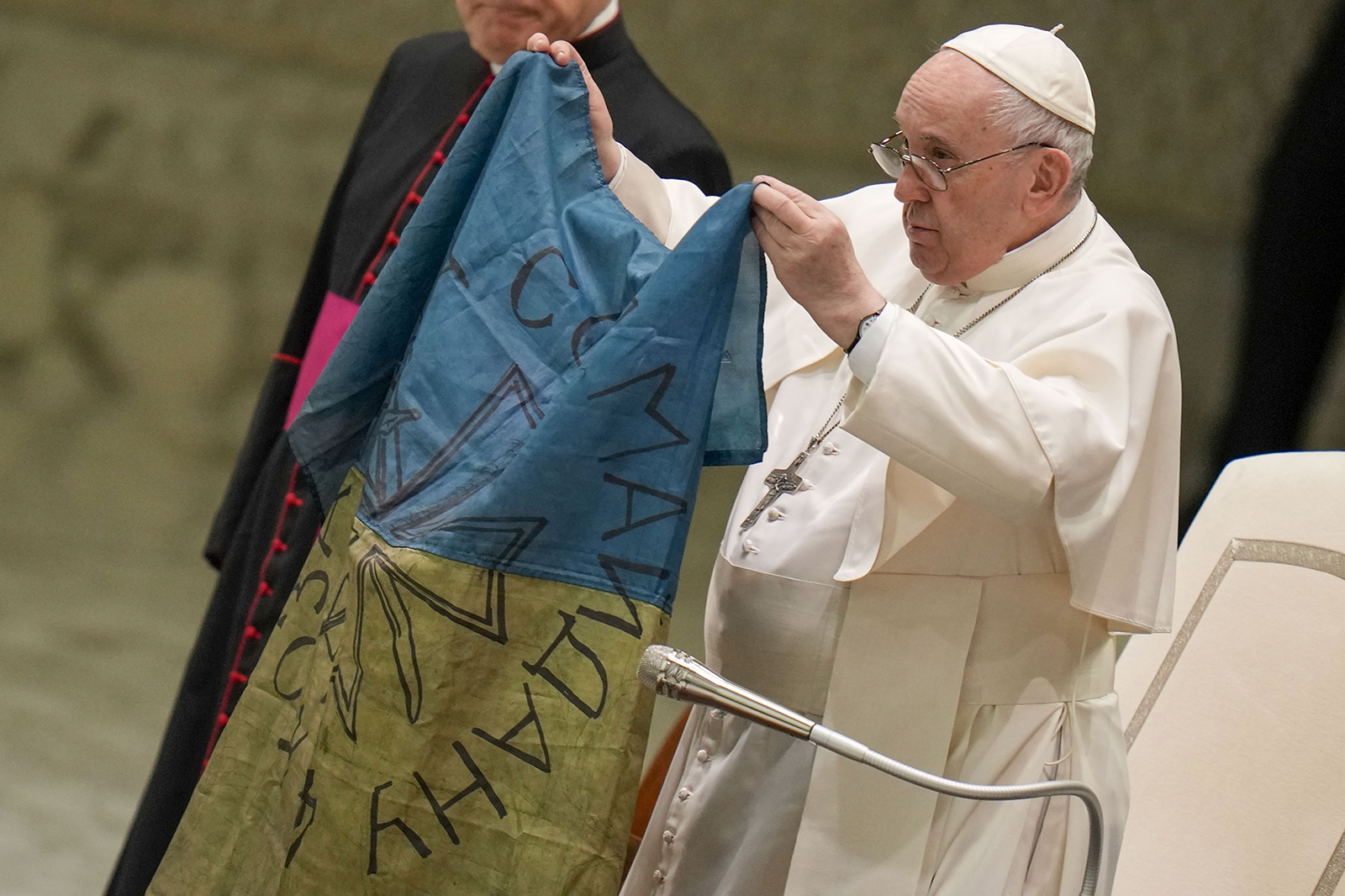 Pope Francis shows a flag that was brought to him from Bucha, Ukraine, during his weekly general audience in the Paul VI Hall, at the Vatican, April 6, 2022. (AP Photo/Alessandra Tarantino)