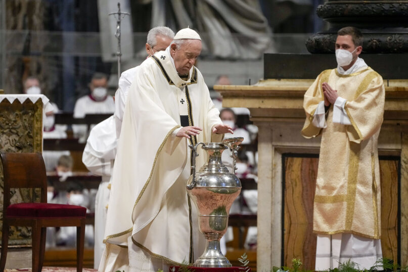 Pope Francis blesses chrism oil contained in a jar during a Chrism Mass inside St. Peter's Basilica, at the Vatican, April 14, 2022. During the Mass, the pontiff blesses a token amount of oil that will be used to administer the sacraments for the year. (AP Photo/Gregorio Borgia)