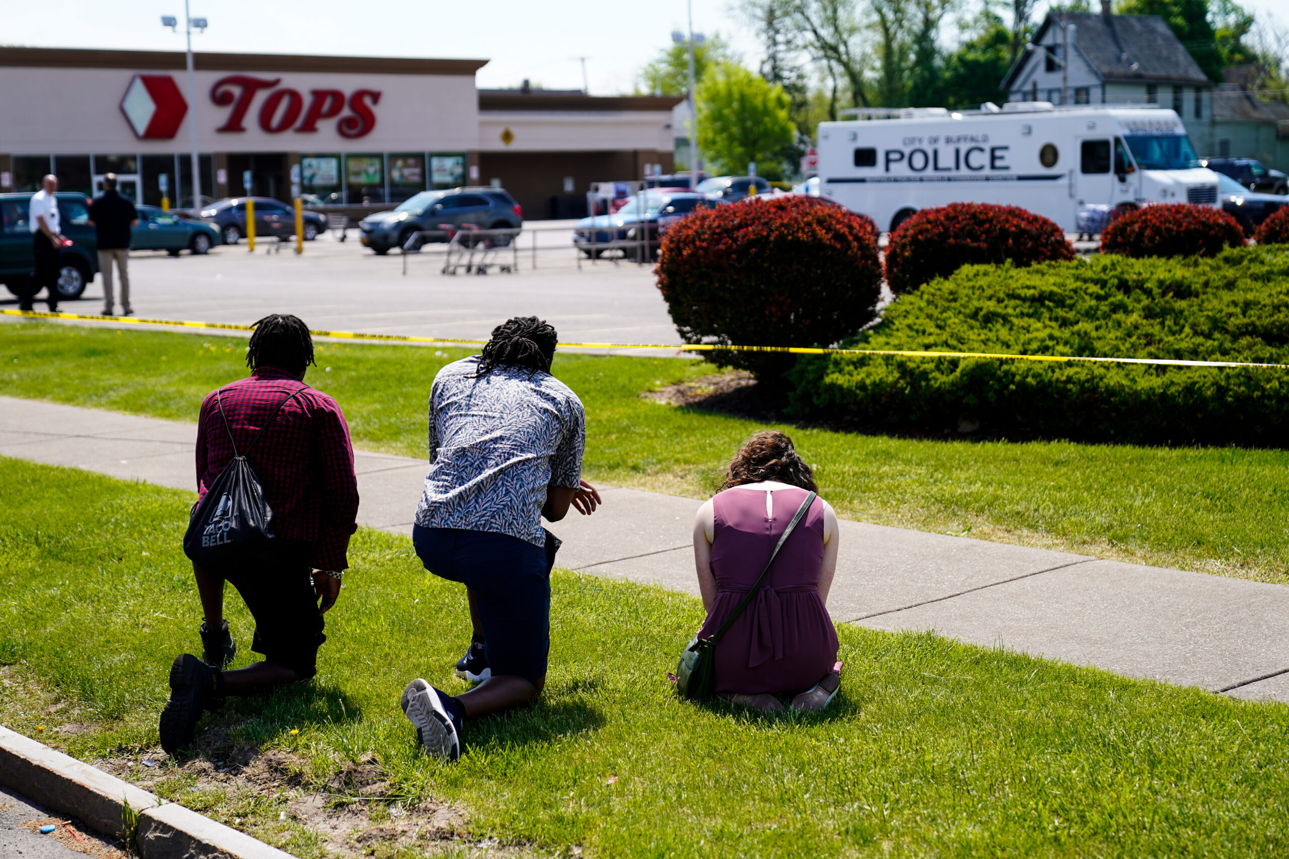 People pray outside the scene of Saturday's shooting at a supermarket, in Buffalo, N.Y., Sunday, May 15, 2022. The shooting is the latest example of something that's been part of U.S. history since the beginning: targeted racial violence. (AP Photo/Matt Rourke)
