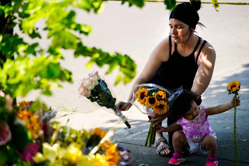 A woman and child place flowers outside the scene of a shooting at a supermarket in Buffalo, New York, May 15, 2022. (AP Photo/Matt Rourke)