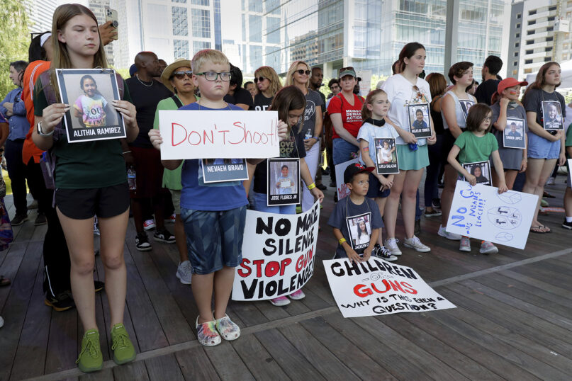 Children hold signs and photos of the Uvalde, Texas, school shooting victims during a rally against gun violence at Discovery Green Park, across the street from the National Rifle Association annual meeting held at the George R. Brown Convention Center, May 27, 2022, in Houston. (AP Photo/Michael Wyke)