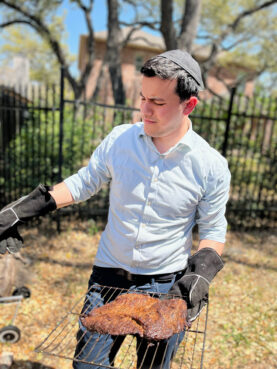 Rabbi Natanel Greenwald, a rabbi at Congregation Rodfei Sholom, prepares brisket in his backyard in San Antonio, Texas. Photo by Rabbi Jeffrey Balaban
