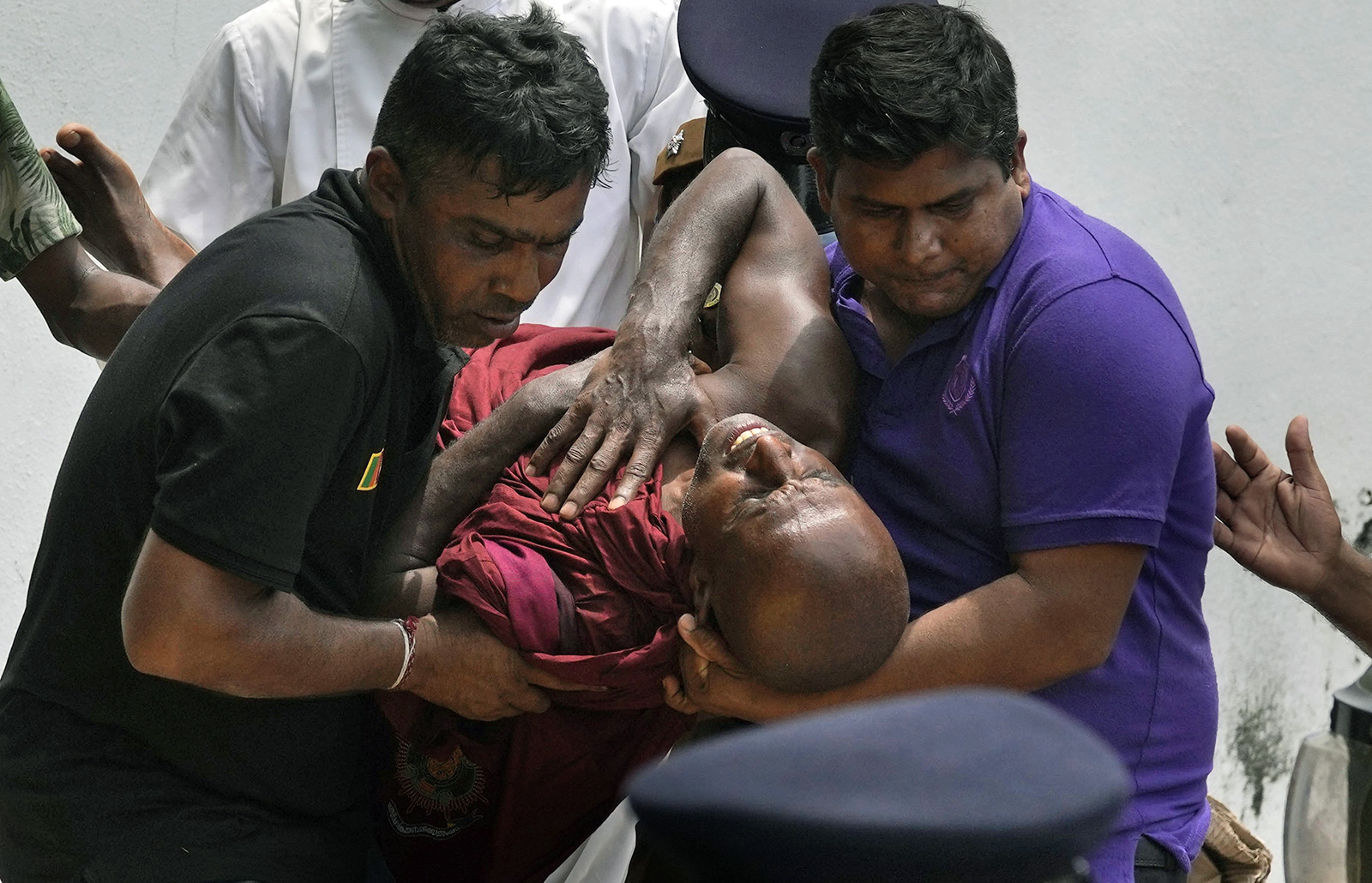 An injured Sri Lankan Buddhist monk is carried away among many other anti-government protesters who were injured after being attacked by pro-government supporters outside prime minister Mahinda Rajapaksa's residence in Colombo, Sri Lanka, Monday, May 9, 2022. Government supporters on Monday attacked protesters who have been camped outside the offices of Sri Lanka's president and prime minster, as trade unions began a “Week of Protests” demanding the government change and its president to step down over the country’s worst economic crisis in memory. (AP Photo/Eranga Jayawardena)