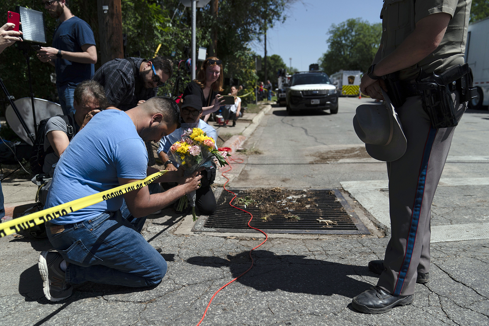 Joseph Avila, left, prays May 25, 2022, while holding flowers honoring the victims killed in Tuesday's shooting at Robb Elementary School in Uvalde, Texas. (AP Photo/Jae C. Hong)