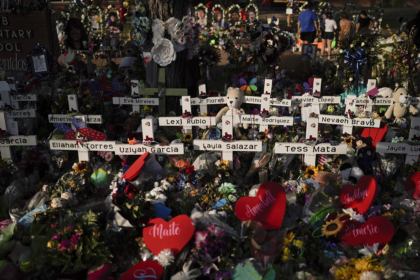 Flowers are piled around crosses with the names of the victims killed in last week's school shooting as people visit a memorial at Robb Elementary School to pay their respects, Tuesday, May 31, 2022, in Uvalde, Texas. (AP Photo/Jae C. Hong)