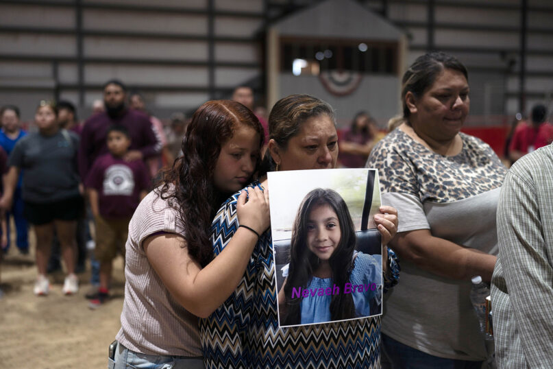Esmeralda Bravo, center, holds a photo of her granddaughter, Nevaeh Bravo, one of the Robb Elementary School shooting victims, as she is comforted by Nevaeh's cousin, Anayeli, during a prayer vigil in Uvalde, Texas, May 25, 2022. (AP Photo/Jae C. Hong)