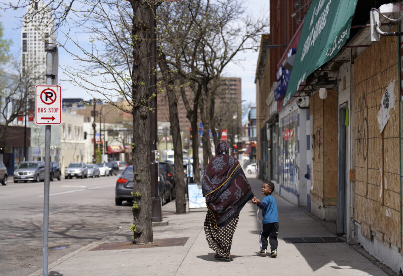 A woman and a child hold hands as they walk down a street in the predominantly Somali neighborhood of Cedar-Riverside in Minneapolis on Thursday, May 12, 2022. (AP Photo/Jessie Wardarski)
