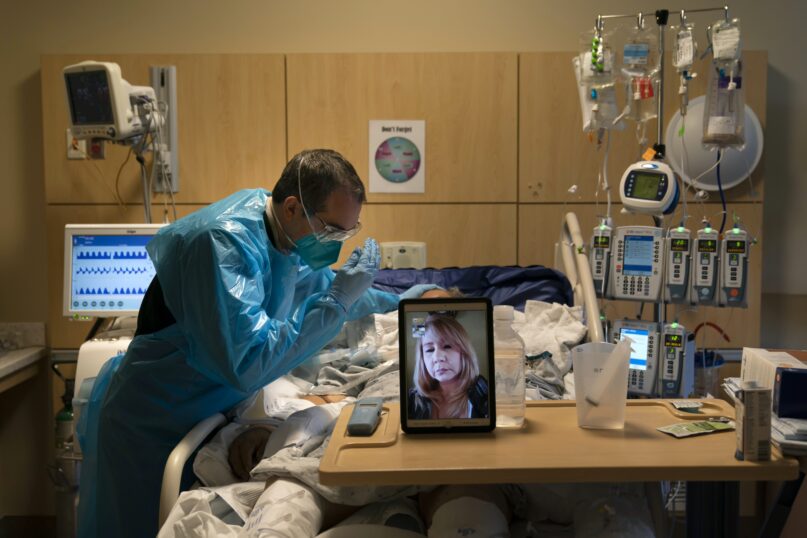 A chaplain prays for a COVID-19 patient in Los Angeles while on a video call with the patient's daughter in November 2020. (AP Photo/Jae C. Hong)