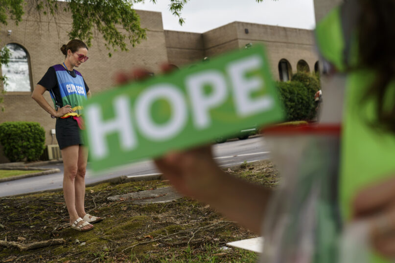 Planned Parenthood advocacy programs manager Allison Terracio, left, stands outside the clinic to escort patients showing up for abortion appointments as Valerie Berry, program manager for the anti-abortion group A Moment of Hope, holds up a sign at the entrance in Columbia, South Carolina, May 27, 2022. After decades of tiny steps and endless setbacks, America’s anti-abortion movement is poised for the possibility of a massive leap. With the Supreme Court due to deliver a landmark ruling expected to seriously curtail or completely overturn the constitutional right to abortion found in the 49-year-old Roe v. Wade decision, anti-abortion advocates across the U.S. are hopeful they’ll be recording a win. (AP Photo/David Goldman)