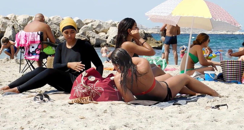 In this image taken from video, Nesrine Kenza, left, and two unidentified friends rest on the beach in Marseille, France, Monday Aug. 29, 2016. (AP Photo)