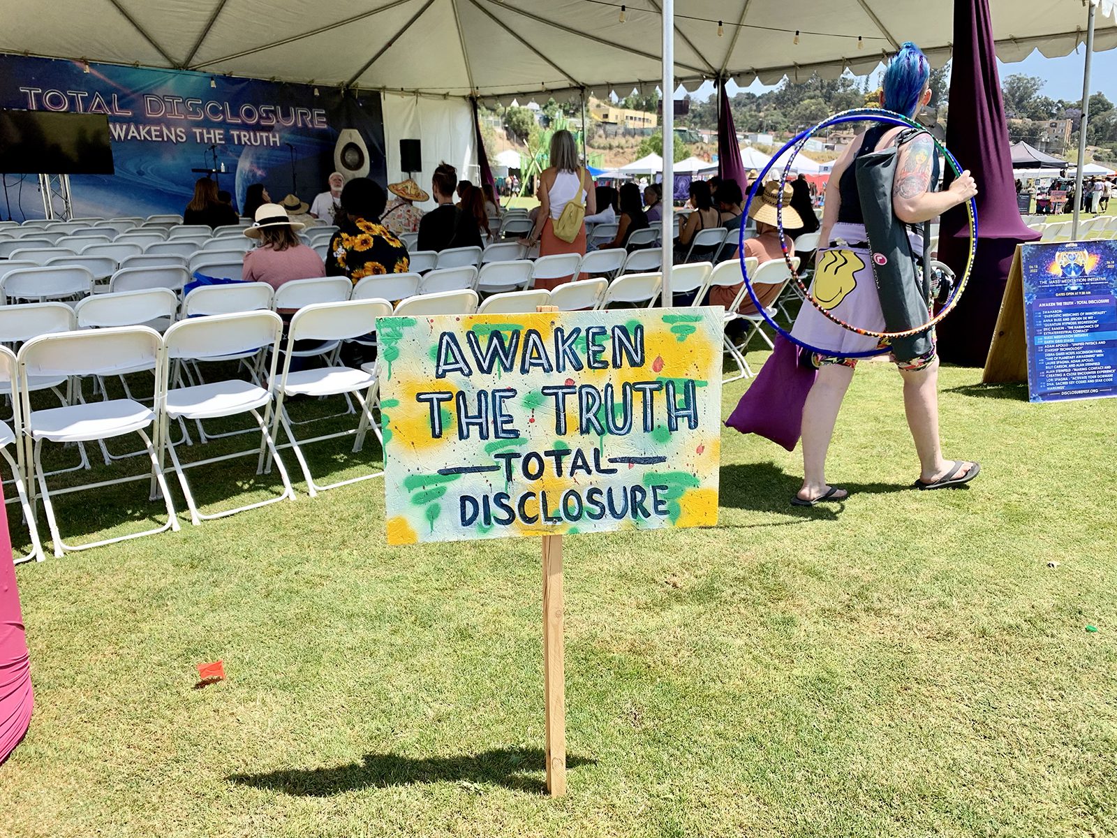 An attendee carries hula hoops and a yoga mat past a session at DisclosureFest, Saturday, June 18, 2022, at the Los Angeles State Historic Park. Photo by Sam Kestenbaum